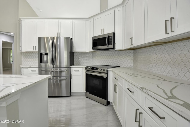 kitchen featuring decorative backsplash, light stone counters, marble finish floor, stainless steel appliances, and white cabinetry