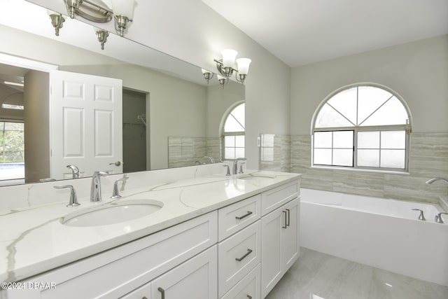 full bathroom with a garden tub, double vanity, a sink, and a chandelier