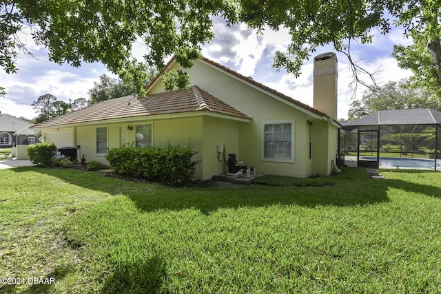 back of house featuring glass enclosure, a chimney, stucco siding, and a yard