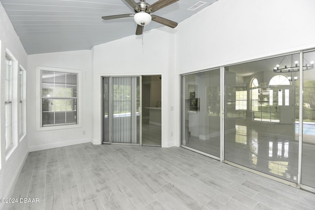 unfurnished sunroom with lofted ceiling, visible vents, plenty of natural light, and a ceiling fan