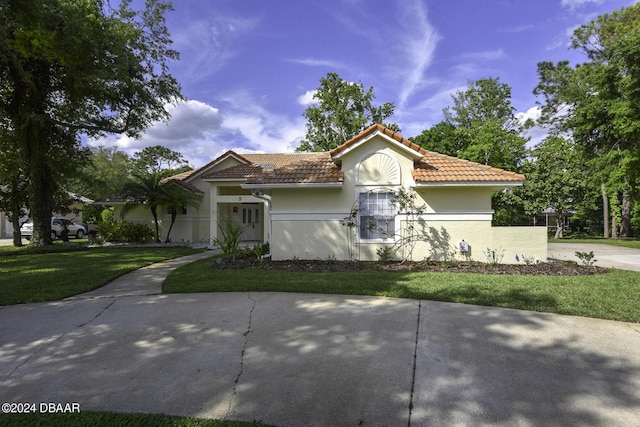 mediterranean / spanish-style home featuring a tile roof, a front lawn, and stucco siding