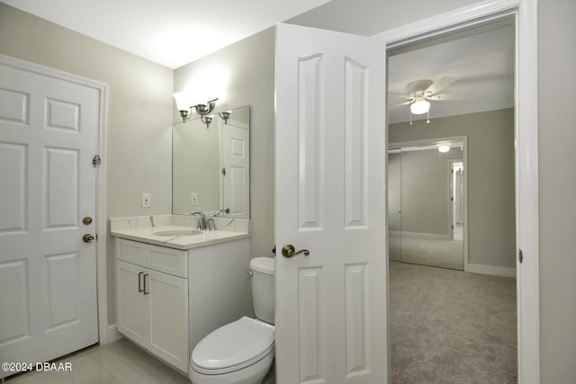 half bath with baseboards, ceiling fan, vanity, and toilet