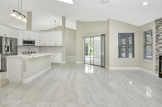 kitchen featuring a fireplace, appliances with stainless steel finishes, vaulted ceiling, and backsplash