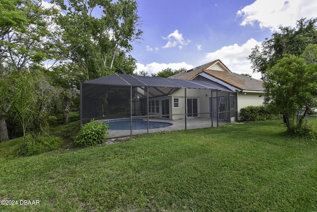 back of property featuring an outdoor pool, a lanai, a yard, a patio area, and stucco siding