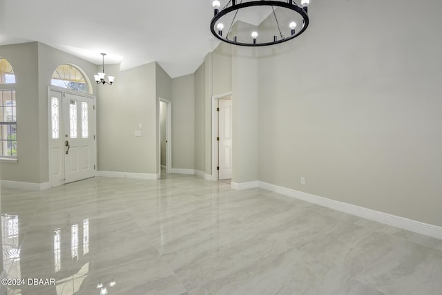 foyer featuring a towering ceiling, plenty of natural light, baseboards, and a notable chandelier