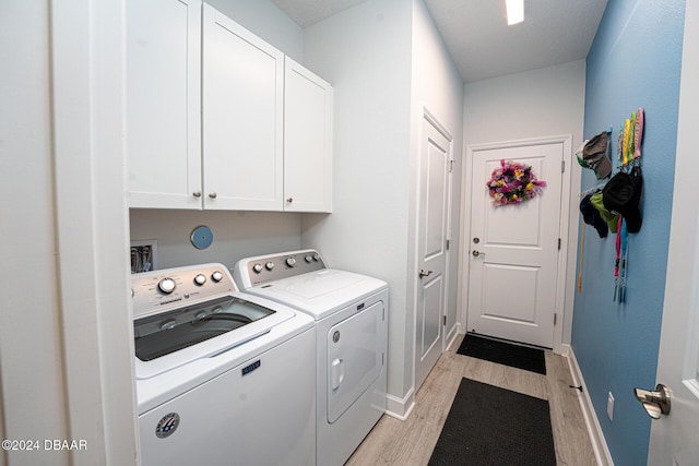 laundry area featuring cabinets, a textured ceiling, separate washer and dryer, and light hardwood / wood-style flooring