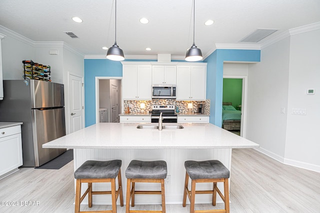 kitchen with light wood-type flooring, stainless steel appliances, white cabinetry, and a center island with sink