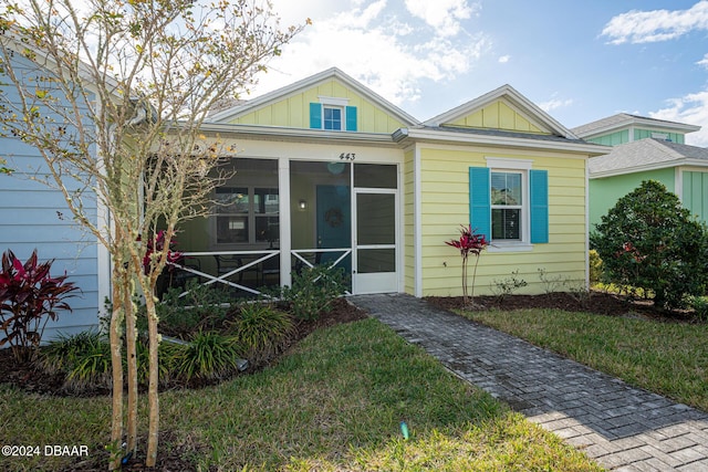 bungalow-style home with a front lawn and a sunroom