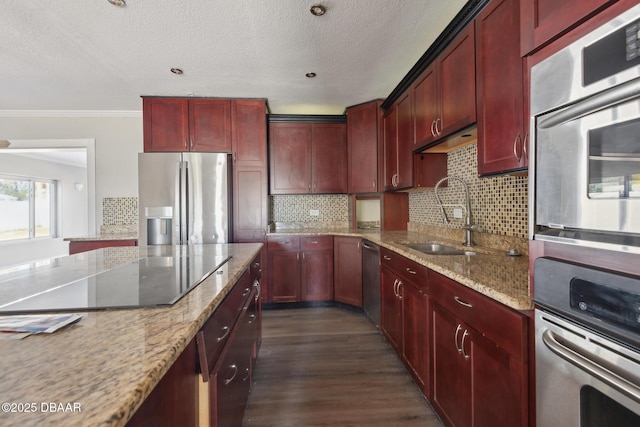 kitchen with light stone counters, ornamental molding, stainless steel appliances, dark wood-type flooring, and sink