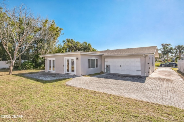 rear view of house with a yard, french doors, and a garage