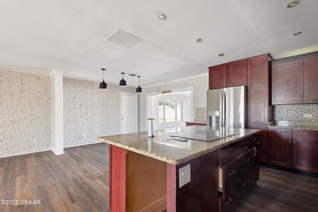 kitchen featuring a center island, hanging light fixtures, stainless steel fridge, light stone countertops, and dark hardwood / wood-style flooring