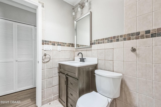 bathroom with vanity, crown molding, hardwood / wood-style flooring, tile walls, and toilet