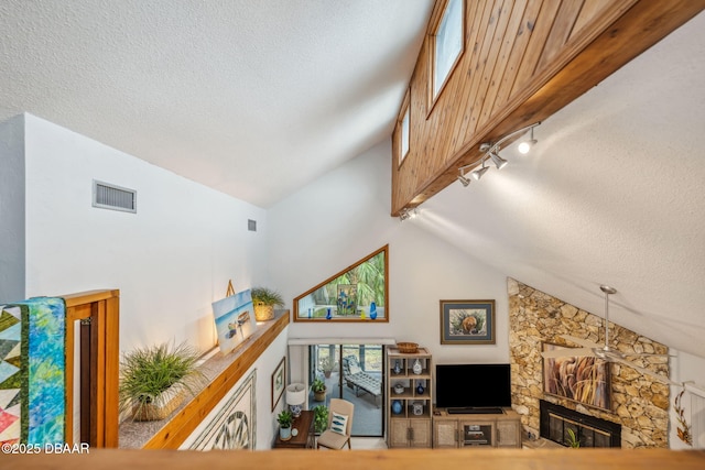 living room with vaulted ceiling, a fireplace, and track lighting