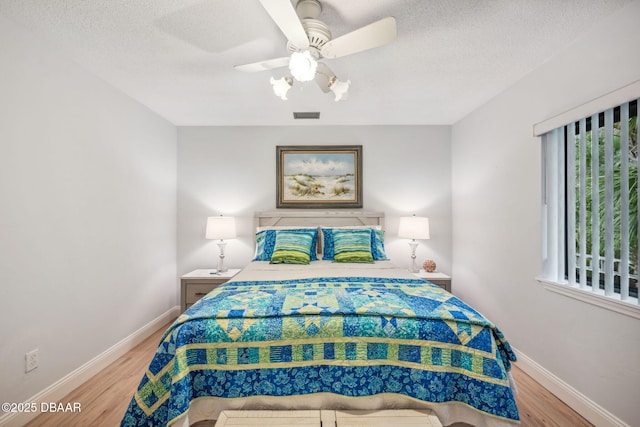 bedroom with ceiling fan, light hardwood / wood-style floors, and multiple windows