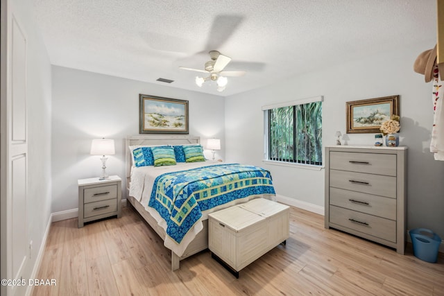 bedroom with ceiling fan, a textured ceiling, and light hardwood / wood-style flooring