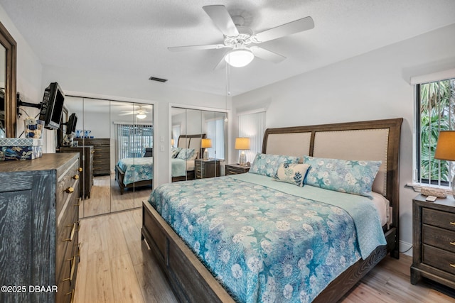 bedroom featuring ceiling fan, light hardwood / wood-style floors, multiple windows, and a textured ceiling