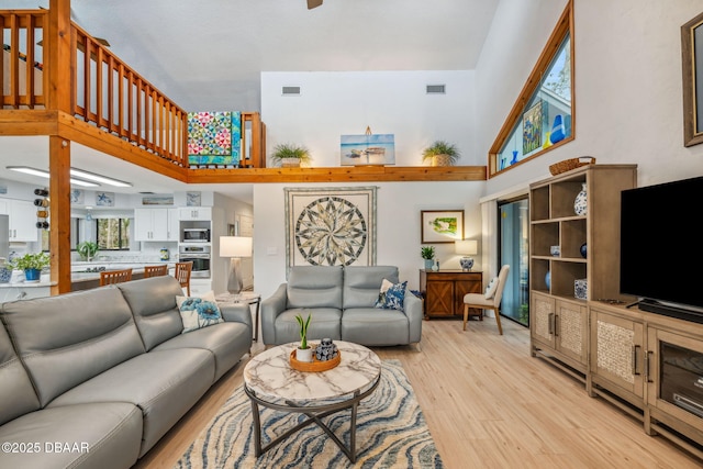 living room featuring a high ceiling and light hardwood / wood-style flooring