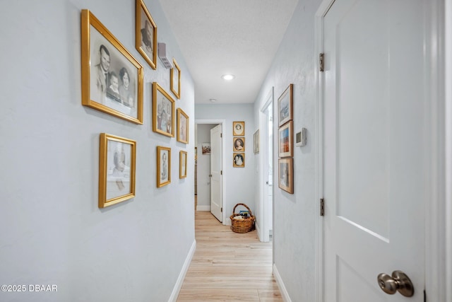 hall with a textured ceiling and light hardwood / wood-style flooring