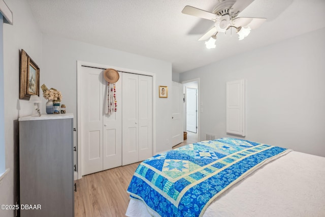 bedroom with ceiling fan, a closet, a textured ceiling, and hardwood / wood-style floors