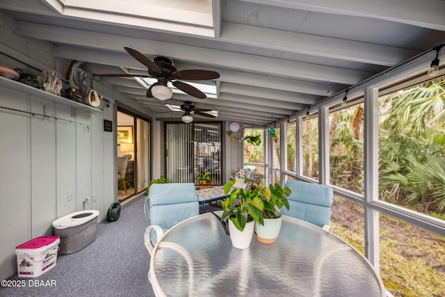 sunroom with ceiling fan and beam ceiling