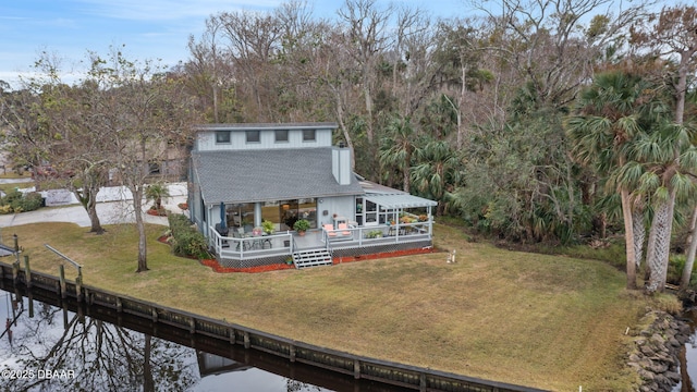 rear view of house with a deck with water view and a lawn