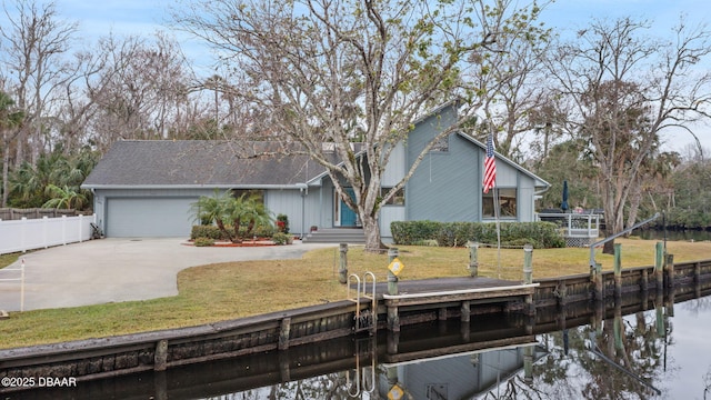 view of front of home with a garage, a front lawn, and a water view