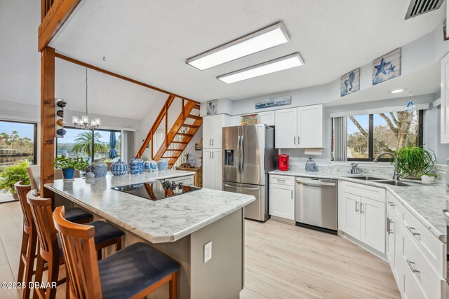 kitchen featuring white cabinets, a center island, stainless steel appliances, sink, and a breakfast bar