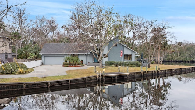 view of front of home with a garage, a front yard, and a water view