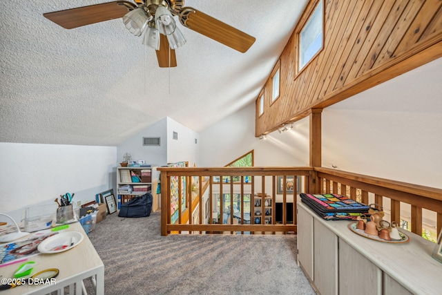 interior space with ceiling fan, a textured ceiling, light carpet, and vaulted ceiling