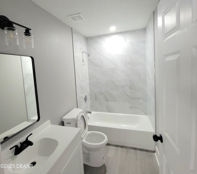 bathroom with visible vents, toilet, wood finished floors, tub / shower combination, and vanity