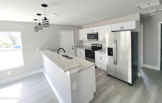 kitchen with visible vents, a peninsula, stainless steel appliances, light wood-style floors, and a sink