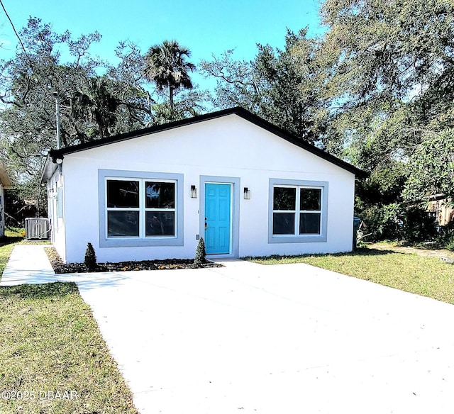 bungalow-style house with cooling unit, a front lawn, and stucco siding