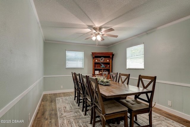2917 Carriage Dr, South Daytona, FL 32119 - dining space featuring wood finished floors, crown molding, a wainscoted wall, a ceiling fan, and a textured ceiling