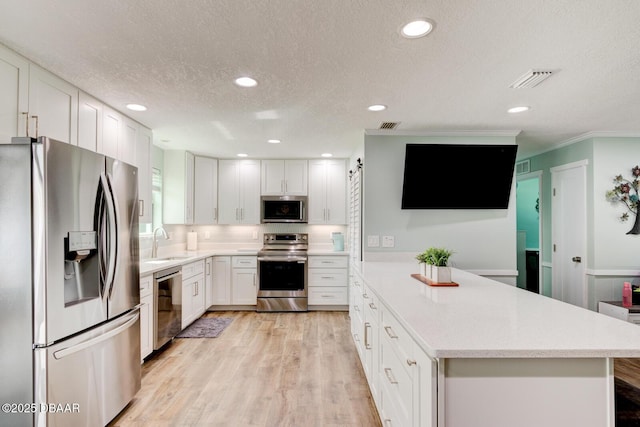 2917 Carriage Dr, South Daytona, FL 32119 - kitchen featuring appliances with stainless steel finishes, white cabinetry, light wood-style floors, a textured ceiling, and recessed lighting