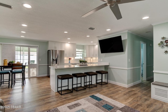 2917 Carriage Dr, South Daytona, FL 32119 - kitchen with ornamental molding, a peninsula, stainless steel fridge with ice dispenser, white cabinetry, and ceiling fan
