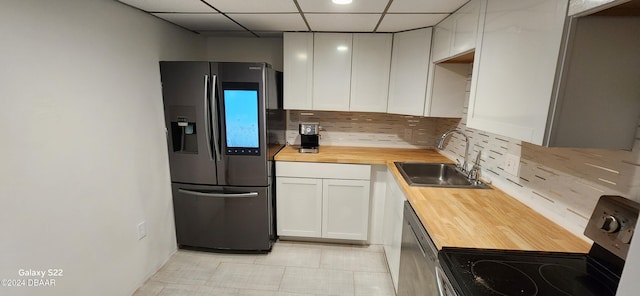 kitchen featuring a drop ceiling, sink, decorative backsplash, white cabinetry, and stainless steel appliances