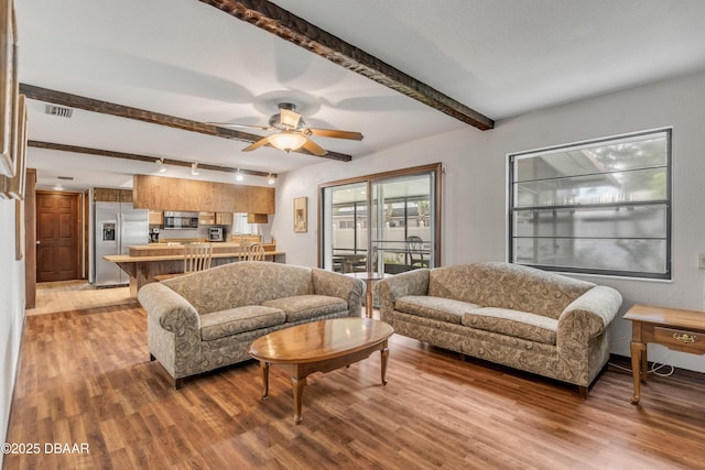 living room with hardwood / wood-style floors, ceiling fan, and beam ceiling