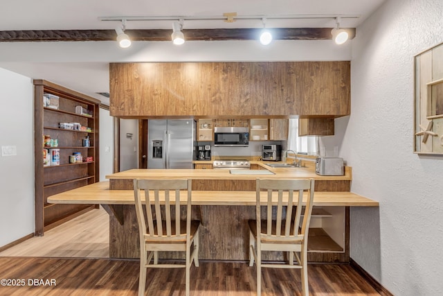 kitchen featuring track lighting, stainless steel appliances, hardwood / wood-style flooring, and sink