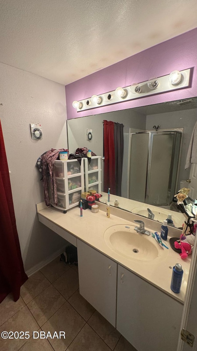 bathroom featuring tile patterned flooring, vanity, a stall shower, and a textured ceiling