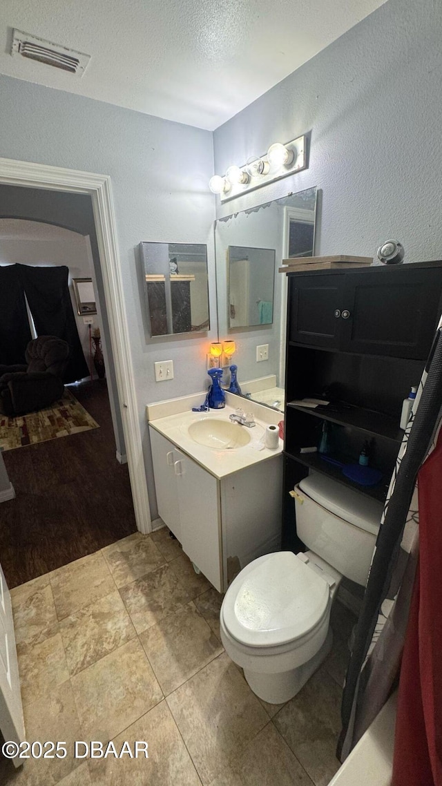 bathroom with tile patterned floors, toilet, vanity, a textured ceiling, and visible vents