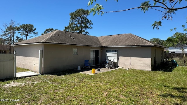 rear view of property with concrete block siding, a shingled roof, fence, and a yard