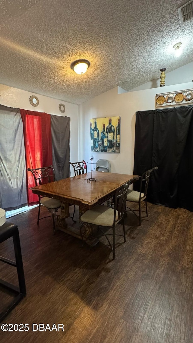 dining area with visible vents, a textured ceiling, vaulted ceiling, and wood finished floors