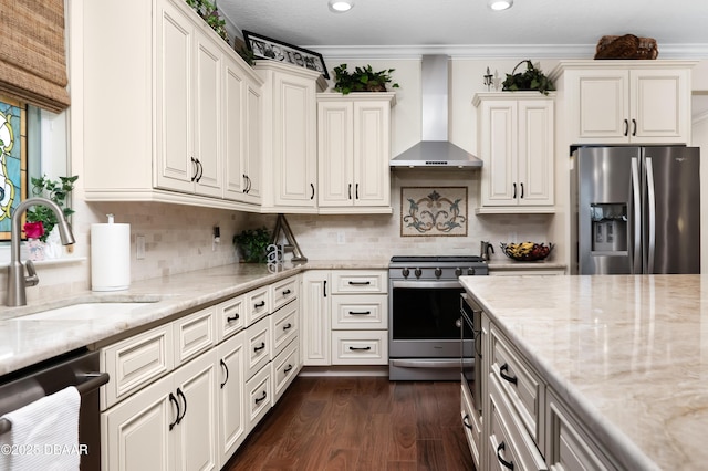 kitchen featuring light stone counters, sink, appliances with stainless steel finishes, and wall chimney exhaust hood