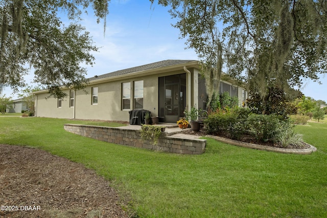 rear view of house featuring a lawn and a sunroom