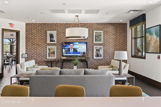 living room with brick wall, a healthy amount of sunlight, and hardwood / wood-style flooring