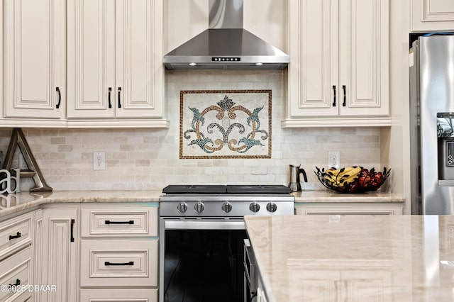 kitchen with light stone counters, appliances with stainless steel finishes, wall chimney exhaust hood, and tasteful backsplash