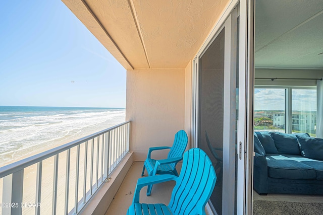 balcony featuring a water view and a beach view