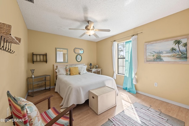 bedroom featuring a textured ceiling, light hardwood / wood-style floors, and ceiling fan