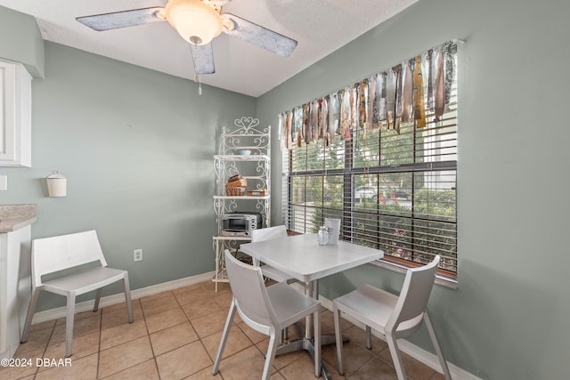 tiled dining area with a textured ceiling and ceiling fan