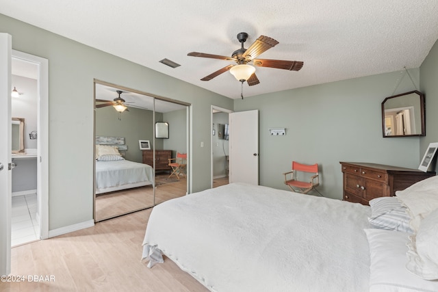 bedroom with a textured ceiling, light hardwood / wood-style flooring, ceiling fan, and connected bathroom